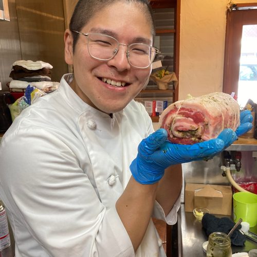 仕込み中の豚バラ肉を持つシェフ