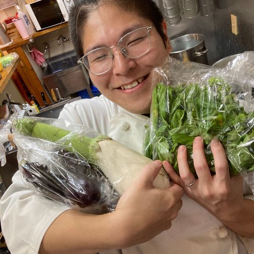 野菜とバジルを抱えるシェフ